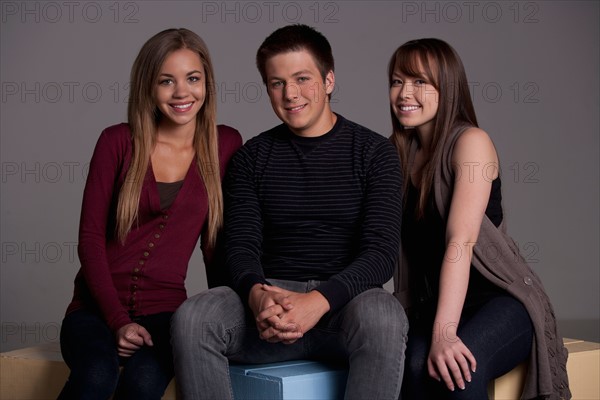 Portrait of teenage boy (16-17) and girl (16-17) with young friend, studio shot. Photo: Rob Lewine