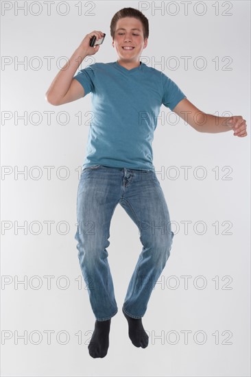 Portrait of teenage boy (16-17) jumping, studio shot. Photo : Rob Lewine