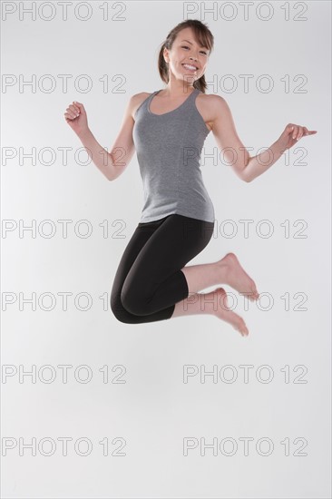 Portrait of young woman jumping, studio shot. Photo : Rob Lewine