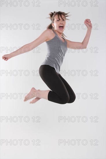 Portrait of young woman jumping, studio shot. Photo : Rob Lewine