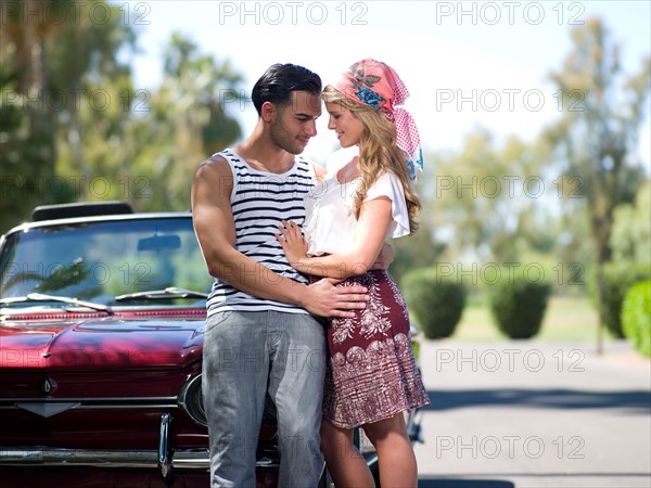 Couple embracing near convertible car. Photo : db2stock