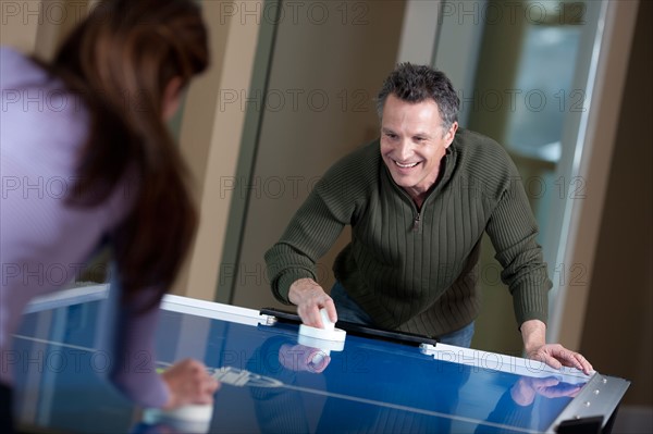 Couple playing air hockey. Photo : db2stock