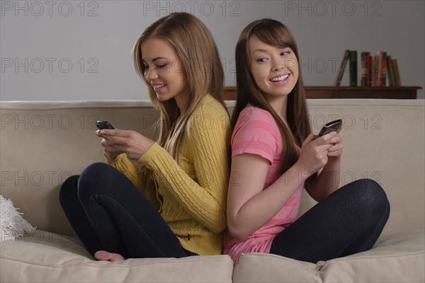 Portrait of teenage girl (16-17) with young woman sitting on sofa. Photo : Rob Lewine