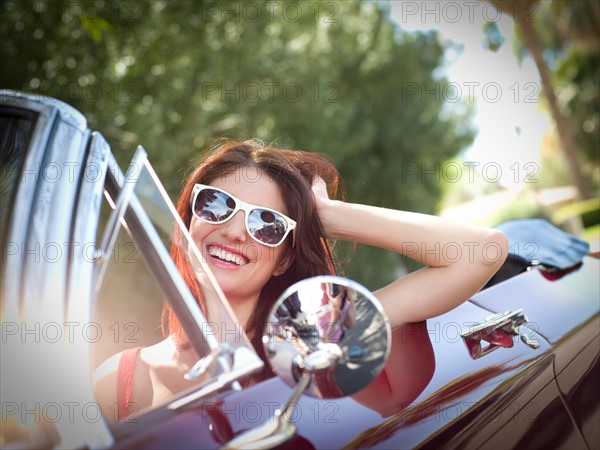 Smiling young woman in convertible car. Photo : db2stock