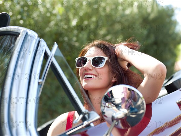 Smiling young woman in convertible car. Photo : db2stock