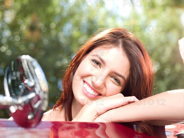 Smiling young woman in convertible car. Photo: db2stock