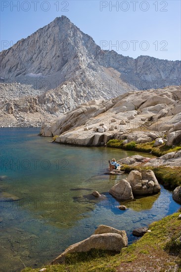 USA, California, Sequoia National Park, Five Lakes trail, Hiker sitting at edge of lake. Photo: Noah Clayton