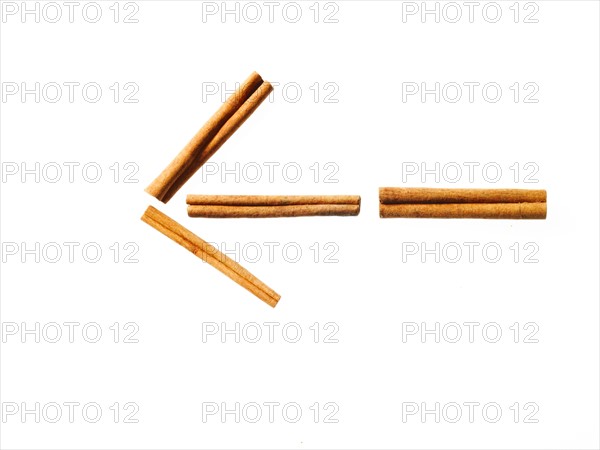 Studio shot of Cinnamon Sticks making Arrow sign on white background. Photo : David Arky