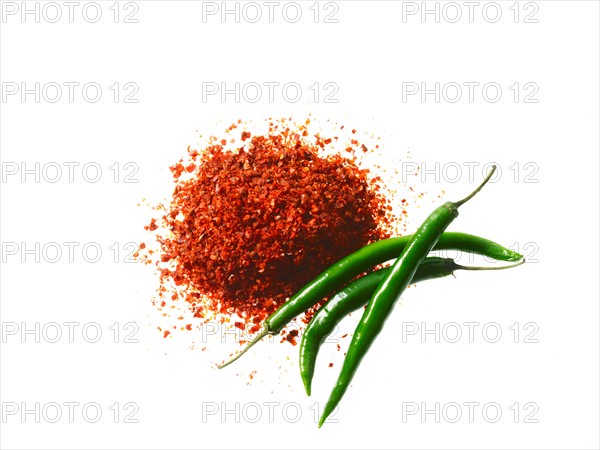 Studio shot of Red Chili Powder and Whole Green Chilies on white background. Photo : David Arky