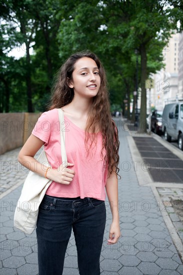 USA, New York, New York City, Portrait of smiling young woman standing on street. Photo: Winslow Productions