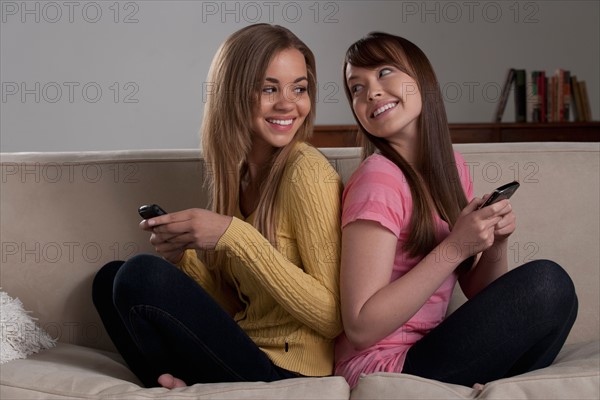 Portrait of teenage girl (16-17) with young woman sitting on sofa. Photo : Rob Lewine