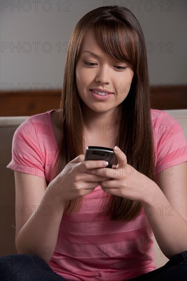 Portrait of young woman with mobile phone, studio shot. Photo : Rob Lewine