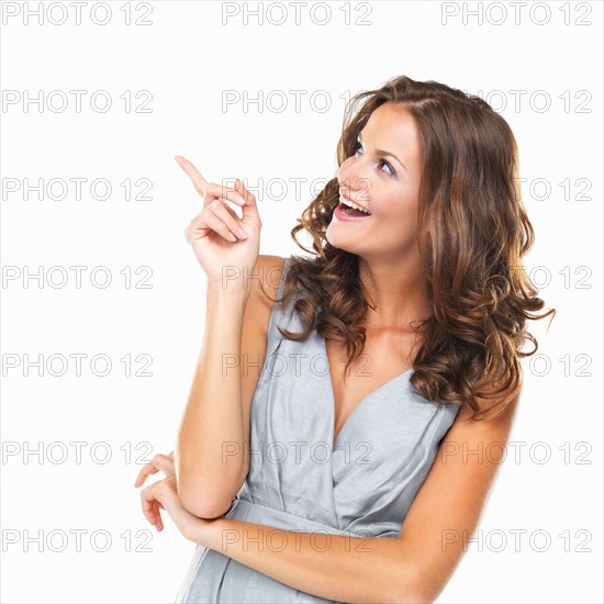 Studio portrait of beautiful smiling woman pointing upwards and smiling. Photo: momentimages