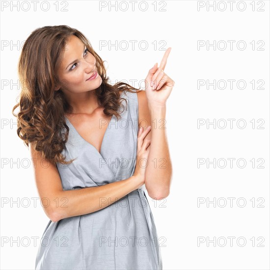 Studio portrait of beautiful smiling woman pointing at copyspace. Photo: momentimages