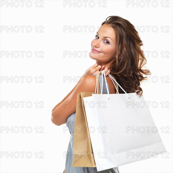 Studio portrait of happy woman holding shopping bags and looking over her shoulder. Photo: momentimages