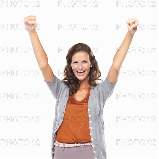 Studio portrait of woman enjoying success with hands raised. Photo: momentimages