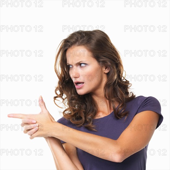 Studio portrait of making gun shape with both hands and pointing away. Photo : momentimages