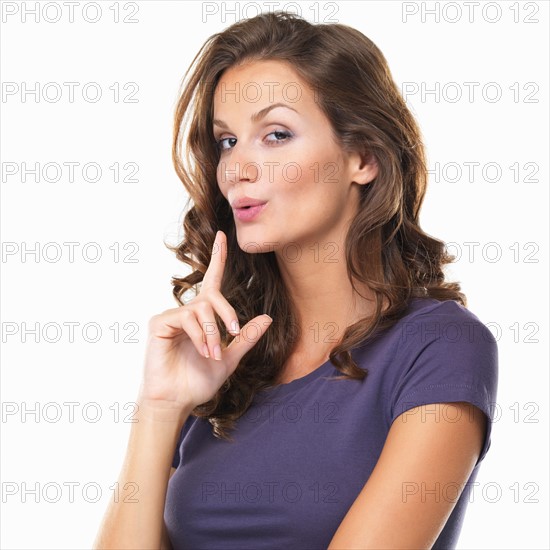 Studio portrait of beautiful woman making gun shape with hand and blowing off imaginative smoke. Photo : momentimages