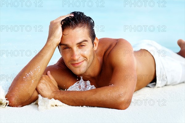 Smart young man relaxing on beach. Photo: momentimages