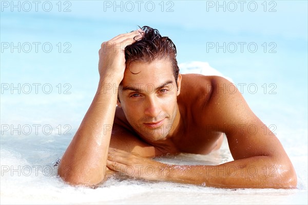 Portrait of attractive young man relaxing on beach. Photo : momentimages