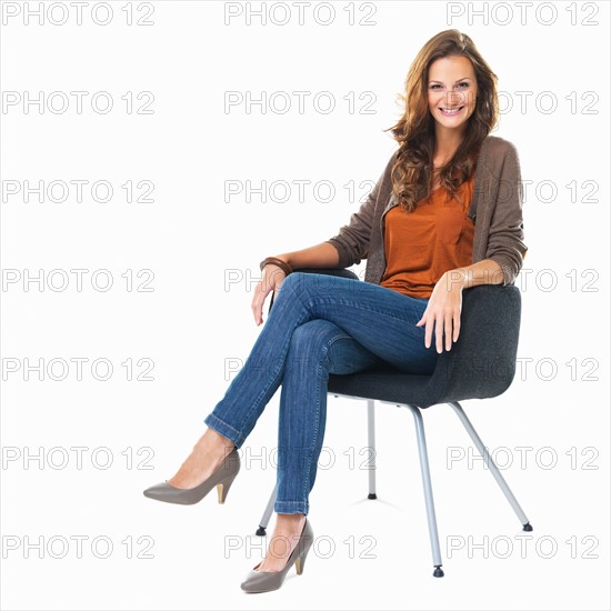 Studio shot of young woman sitting in chair. Photo : momentimages