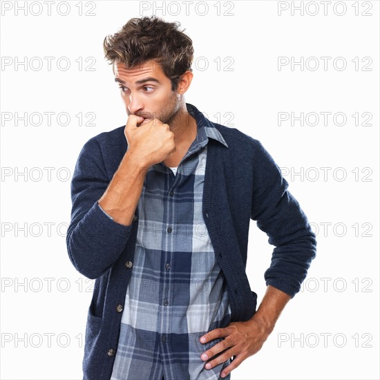 Studio shot of young man biting nails and looking away. Photo : momentimages