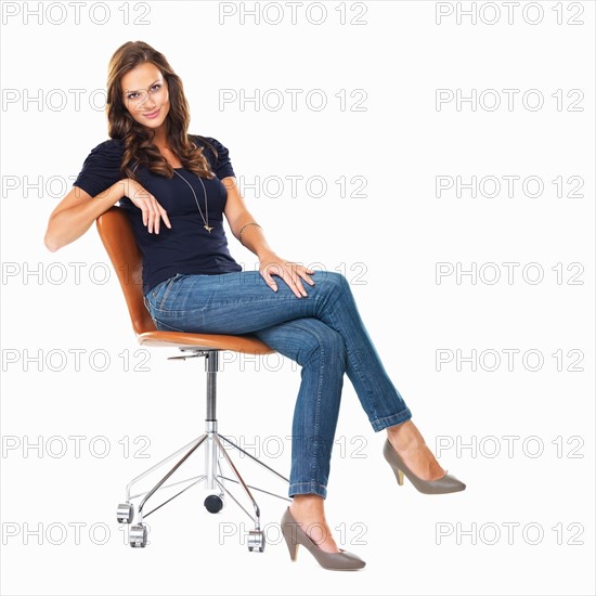 Studio shot of young relaxed woman sitting on chair. Photo : momentimages