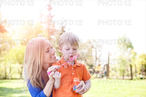 Mother and son (2-3) blowing bubbles in park. Photo : Take A Pix Media