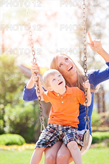 USA, Washington State, Seattle, Mother and son (2-3) swinging on swing in park. Photo : Take A Pix Media