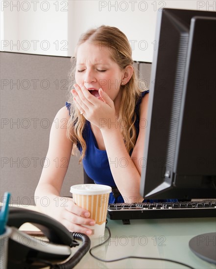 Young woman yawning in office. Photo: Jamie Grill