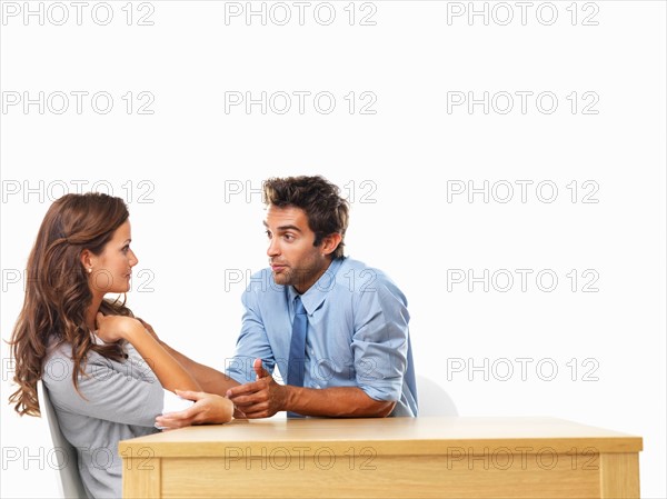 Business couple sitting at table and talking to each other. Photo: momentimages