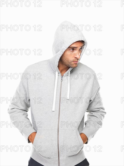 Young man in hoodie standing with hands in pockets. Photo : momentimages