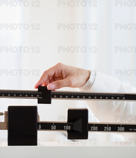 Close up of female doctor's hand holding scale. Photo : Jamie Grill