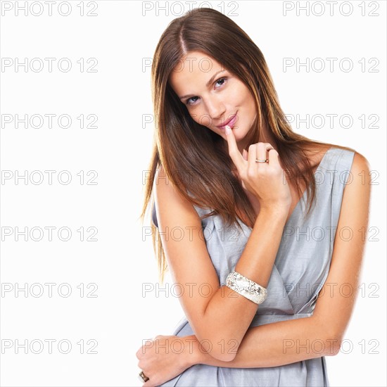 Portrait of attractive woman smiling with finger on lip against white background. Photo: momentimages
