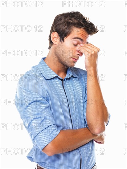 Stressed male executive standing and rubbing nose. Photo : momentimages