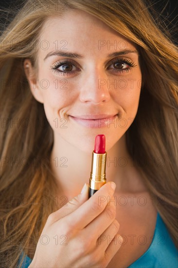 Portrait of woman holding lipstick. Photo: Jamie Grill