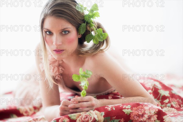 Studio portrait of young woman with flowers in hair.