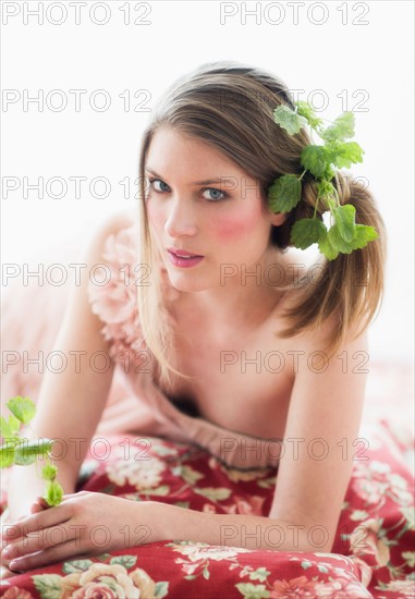 Studio portrait of young woman with flowers in hair.