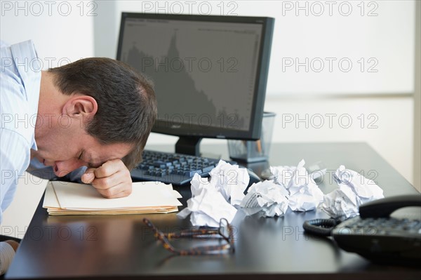 Businessman with face down on desk.