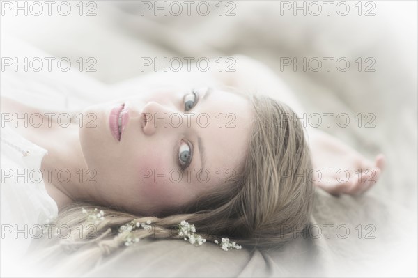 Studio portrait of young woman lying with flowers in hair.