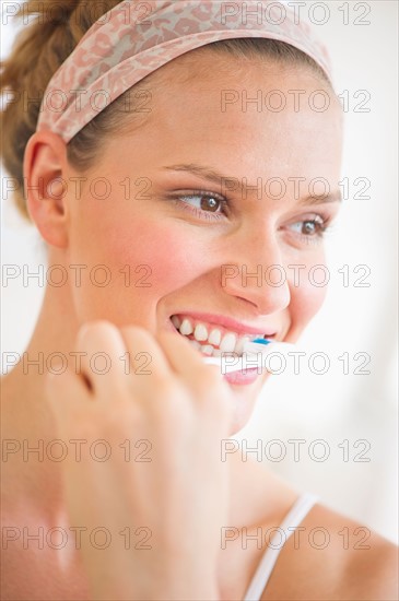 Studio portrait of woman brushing teeth.