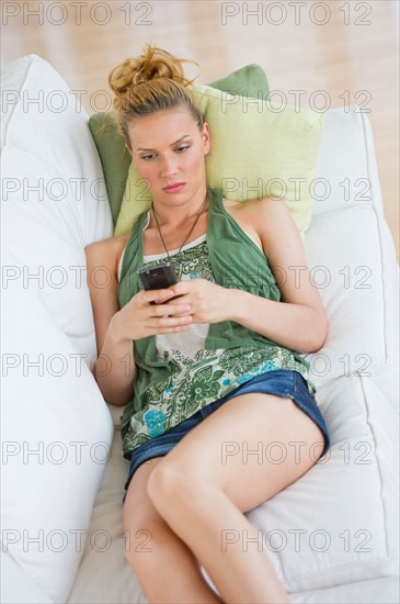 Woman lying on sofa and text messaging.