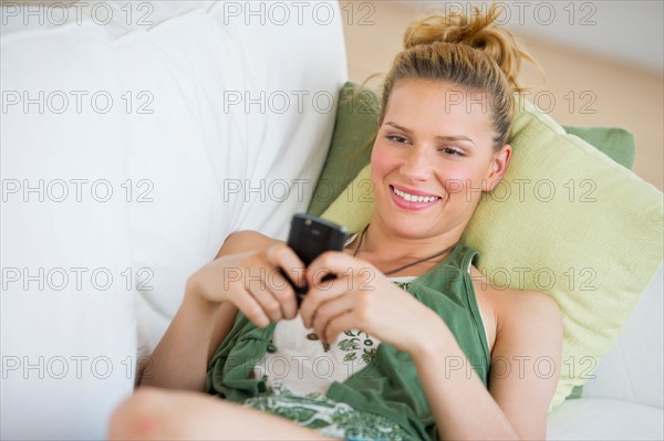 Woman lying on sofa and text messaging.