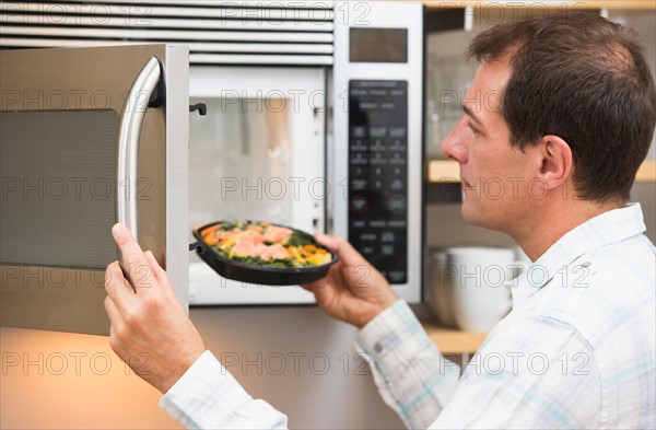 Man inserting meal in microwave oven.