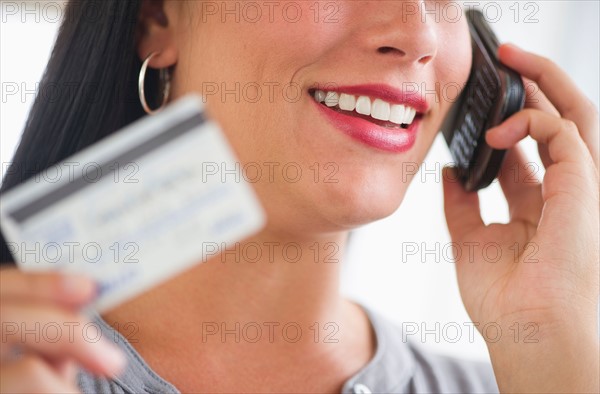 Woman holding credit card and phone.