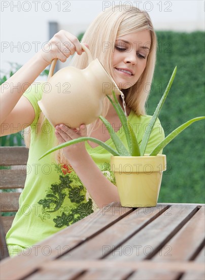 Young woman watering plant. Photo : Jamie Grill