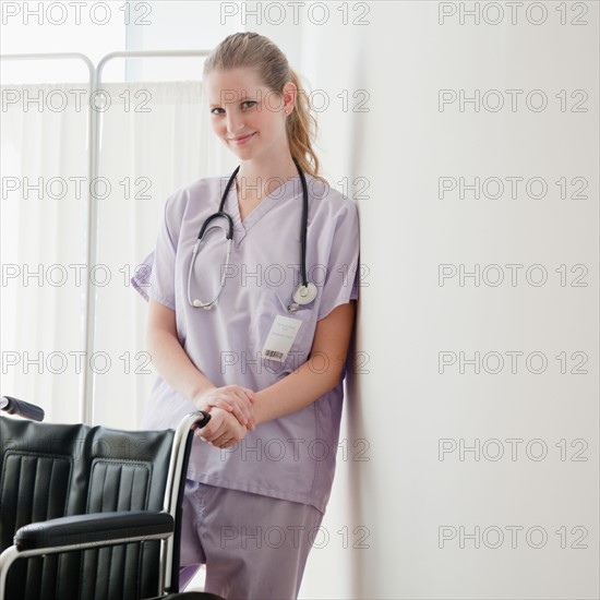 Young nurse standing behind wheelchair. Photo : Jamie Grill