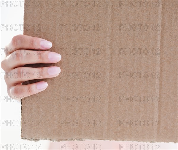 Close up of woman's hand holding cardboard. Photo : Jamie Grill