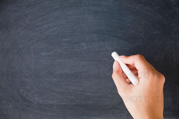 Close up of woman's hands writing with chalk on blackboard. Photo : Jamie Grill