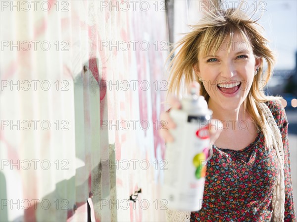 USA, Brooklyn, Williamsburg, Woman spraying with paint can. Photo : Jamie Grill